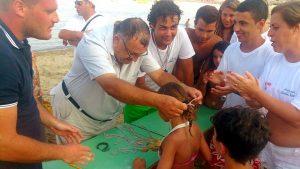 Il sindaco Nello Lo Turco consegna una medaglia ad una bambina partecipante al Naxos Spiaggia Day